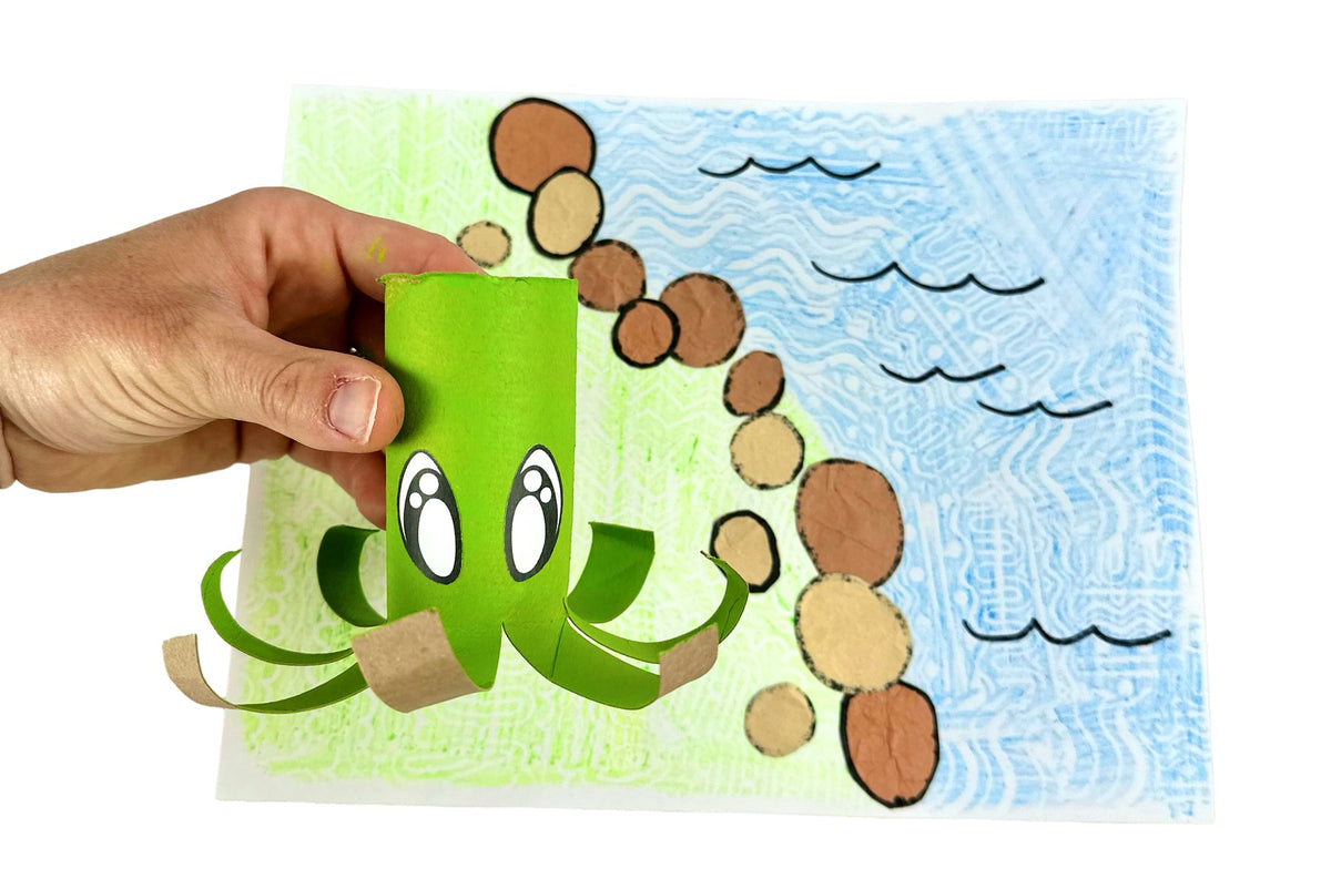 Paper roll Zeek the Octopus craft: a green-painted toilet paper roll with big cartoon eyes and eight curled tentacles, held in front of a crayon-rubbing ocean scene
